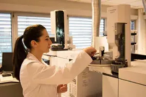 Laboris valge kitliga naisteadlane kasutab kaasaegset analüüsimasinat teaduslike katsete jaoks.
