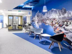 Moderne bürooruumi ootenurk pehmete toolide ja Lofoteni mägede talvise linnavaatega seinamaalinguga.
